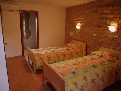 a bedroom with three beds and a stone wall at al Merlo Olivo, rural istrian house in Buje