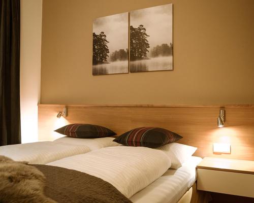 three beds in a room with three paintings on the wall at Apartments Domino in Campo Tures