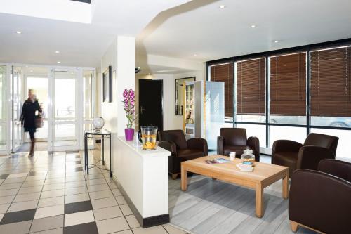 a lobby with chairs and a table and a person at Aparthotel Adagio Access La Défense - Place Charras in Courbevoie