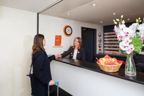 two women are standing at a counter in a salon at Aparthotel Adagio Access La Défense - Place Charras in Courbevoie