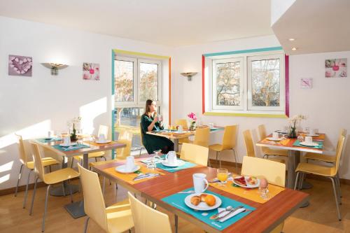 une femme assise à une table dans un restaurant dans l'établissement Aparthotel Adagio Access La Défense - Place Charras, à Courbevoie