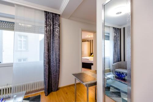 a living room with a window and a mirror at Apartments an der Caracalla Therme in Baden-Baden