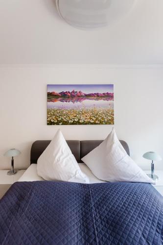 a bedroom with a blue bed with a painting on the wall at Apartments an der Caracalla Therme in Baden-Baden