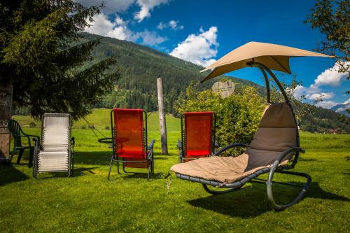 a group of chairs sitting in the grass with an umbrella at Urbangut in Sankt Michael im Lungau