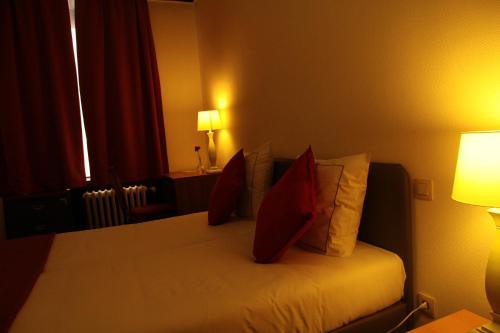 a hotel room with a bed with red pillows at Hotel De Spiegel in Sint-Niklaas