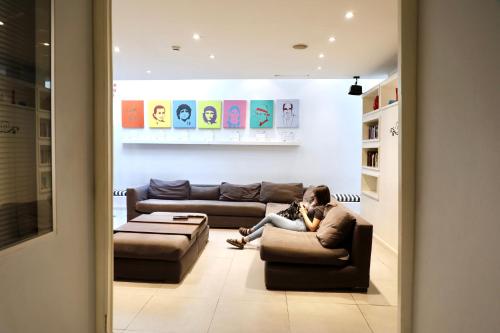 a woman sitting on a couch in a living room at America Del Sur Hostel Buenos Aires in Buenos Aires