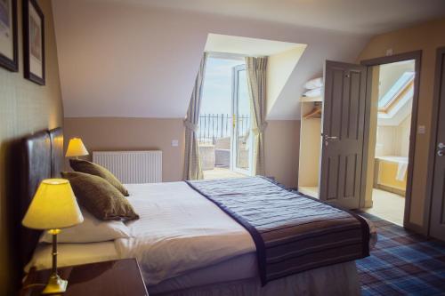 a bedroom with a bed and a door to a balcony at The Bamburgh Castle Inn - The Inn Collection Group in Seahouses