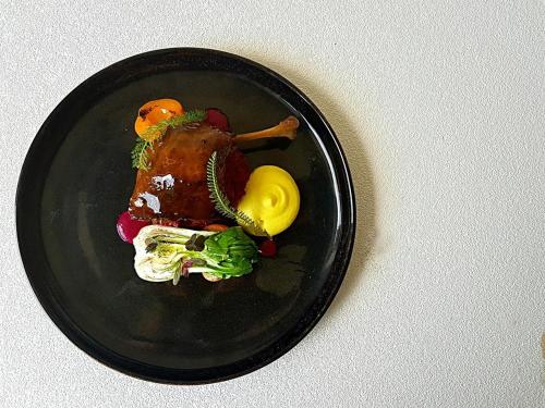 a black plate topped with food on a table at Nova Stodola in Kłomnice