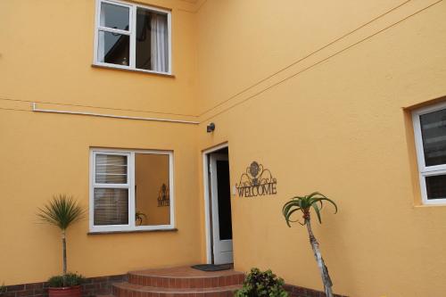 a yellow house with a welcome sign on the side of it at The Timeless Way Self Catering Accommodation in Swakopmund