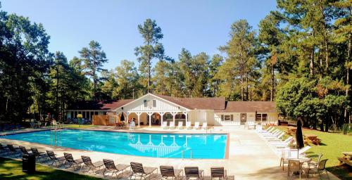 a swimming pool with chairs and a house at Fairfield Plantation Resort in Sand Hill