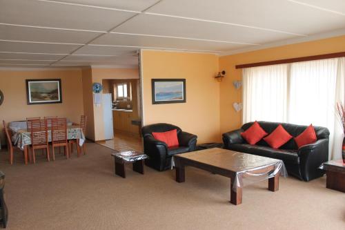 a living room with couches and a table and a kitchen at The Timeless Way Self Catering Accommodation in Swakopmund