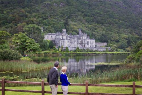 a man and a woman standing in front of a castle at Cottage 173 - Clifden in Clifden