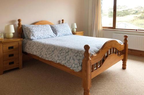 a bedroom with a wooden bed and a window at Cottage 173 - Clifden in Clifden