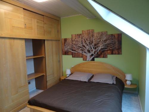 1 dormitorio con 1 cama con un árbol en la pared en Gîte Henry, en Orbey