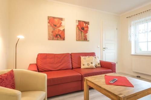 a living room with a red couch and a table at Ferienwohnungen Schön in Teltow