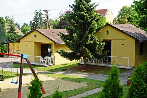 una casa amarilla con un patio de juegos delante de ella en Hotel Magnólia, en Balatonszepezd