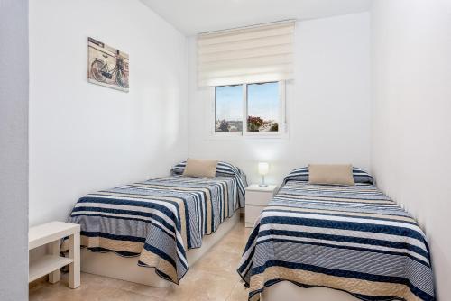 2 camas en una habitación con paredes blancas en WintowinRentals Best Location, Beach, Pool & Parking, en Rincón de la Victoria