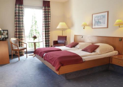 ein Hotelzimmer mit einem großen Bett und einem Stuhl in der Unterkunft Hotel Waldhusen - Adults Only in Kücknitz