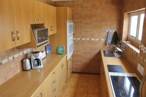 a kitchen with wooden cabinets and a sink and a microwave at The Timeless Way Self Catering Accommodation in Swakopmund
