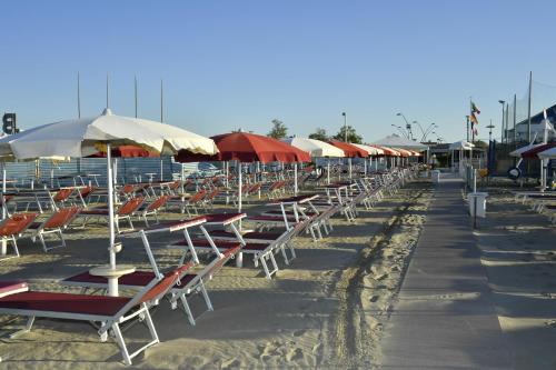a row of chairs and umbrellas on a beach at Pensione Elena in Misano Adriatico