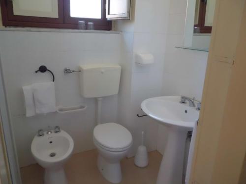 a white bathroom with a toilet and a sink at Etna Wine Azienda Agrituristica in Passopisciaro