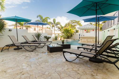 a patio with chairs and umbrellas and a pool at Casa Verde Hotel - Steps to the Beach, Pool, Restaurant & Bar in Rincon