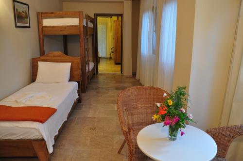 a small room with a bed and a table with flowers on it at Hotel Villa Monte in Cıralı