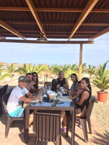a group of people sitting at a table on the beach at El Samay Hotel Boutique in Canoas De Punta Sal