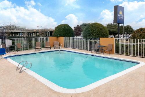 une grande piscine avec des chaises et une table dans l'établissement Days Inn & Suites by Wyndham Arlington Near Six Flags, à Arlington