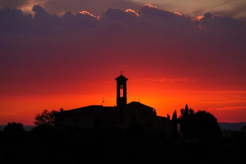 a silhouette of a building with a clock tower at sunset at Castello di Mugnana in Mugnana