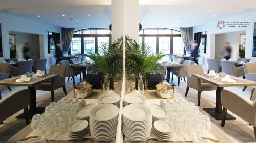 エヴィアン・レ・バンにあるホテル ル ブルゴーニュのレストランのテーブル(皿、グラス付)