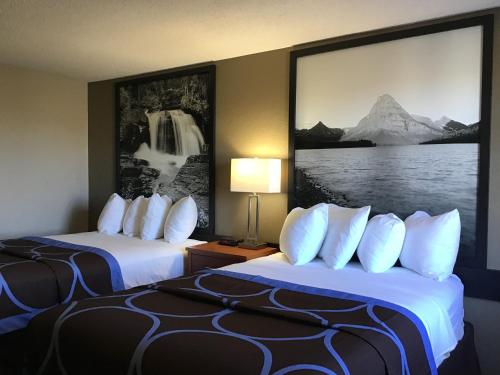 2 camas en una habitación de hotel con una foto en la pared en Super 8 by Wyndham Miles City, en Miles City