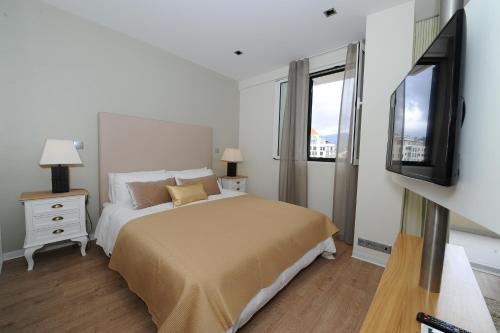 a bedroom with a bed and a flat screen tv at Duas Torres - Appartment in Funchal