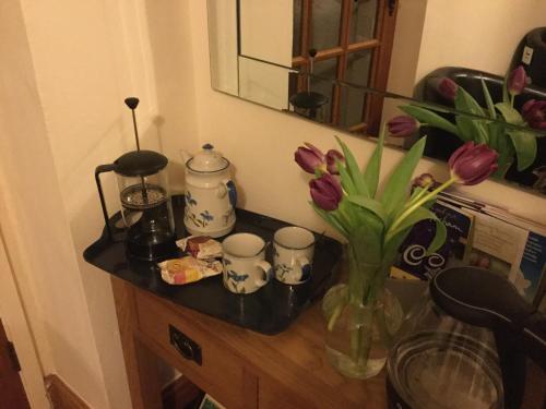 una mesa con un jarrón de flores y tazas. en The Snug @ Corry Cottage en Haltwhistle