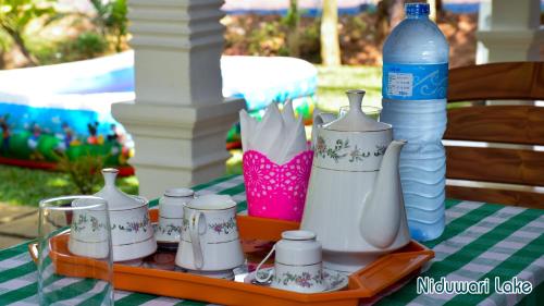 a tray with cups and a bottle of water on a table at Niduwari Lake Homestay in Dambulla