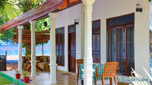 a front porch of a house with a table and chairs at Niduwari Lake Homestay in Dambulla