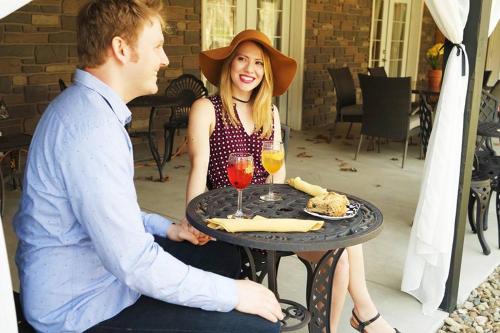 Un uomo e una donna seduti a un tavolo con del cibo di The Inn at Deer Creek Winery a Shippenville