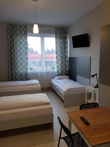 Pokój z 2 łóżkami, stołem i oknem w obiekcie Noclegi MaxTrans w Mielcu