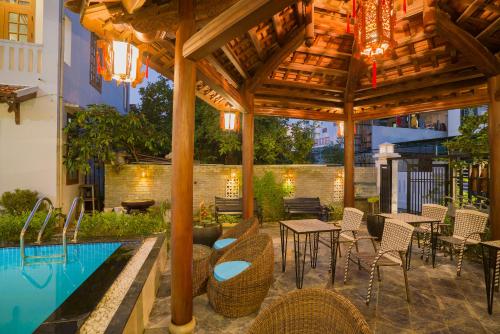 a patio with a table and chairs next to a pool at Green Grapefruit Villa in Hoi An