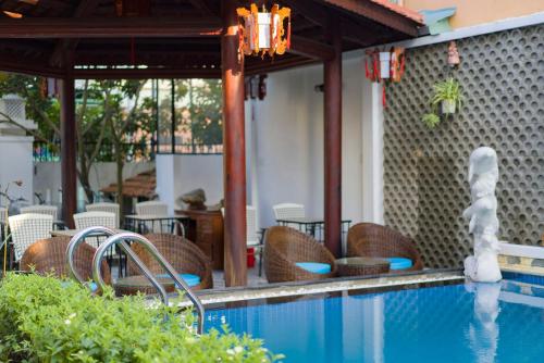 a swimming pool with wicker chairs and a table at Green Grapefruit Villa in Hoi An
