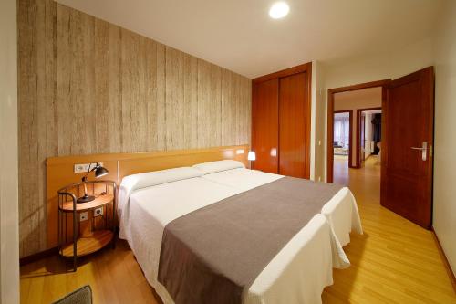 a bedroom with a large white bed and a wooden floor at Apartamentos Urban Blue, Blue Hotels in Gijón