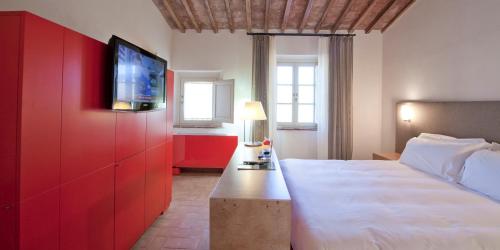 a bedroom with a bed and a tv on a red wall at Locanda Sant'Agata in San Giuliano Terme
