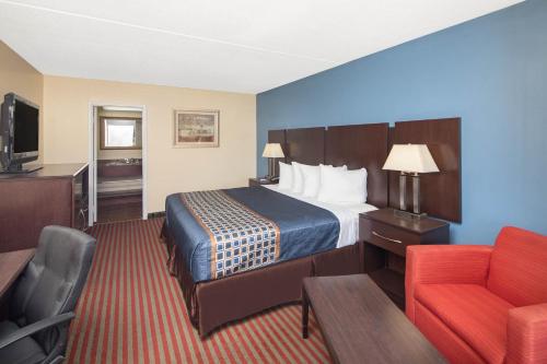 a hotel room with a bed and a red chair at Travelodge by Wyndham Savannah Area/Richmond Hill in Richmond Hill