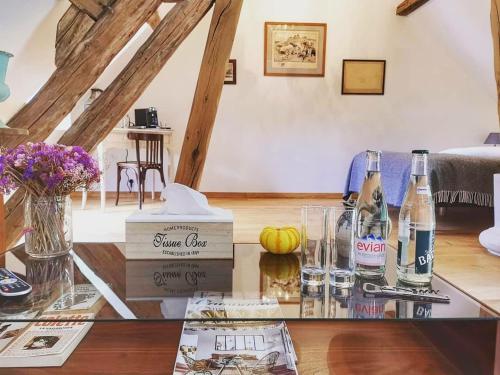 - un salon avec une table en verre et des bouteilles de vin dans l'établissement Le Moulin de Corneil, à Mézilles