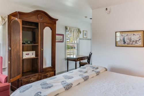 a bedroom with a bed and a wooden cabinet at First Colony Inn in Nags Head