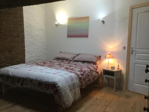 a bedroom with a bed and a table with a lamp at The little house in Mézières-sur-Issoire