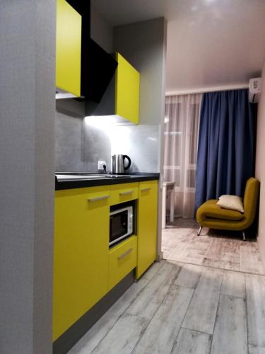 a kitchen with yellow cabinets and a yellow chair at Solo Apartment Kamenskaya in Kyiv