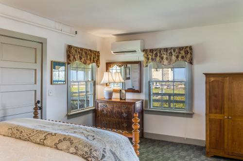 a bedroom with a bed and a dresser and windows at First Colony Inn in Nags Head