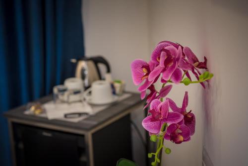 a vase with purple flowers on the wall at B&B Elegance in Taormina