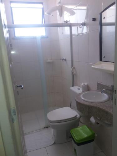a white bathroom with a toilet and a sink at Hotel Praia e Mar in Aracaju